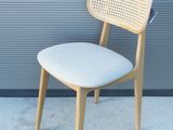 une chaise en bois avec une assise blanche, près d'un mur gris