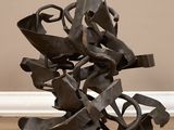 une sculpture en métal posée sur un plancher en bois