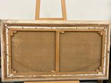an easel with a painting on it sitting next to a stool