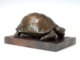 statue d'une tortue posée sur un socle en bois, sur fond blanc