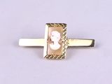a close up of a gold tie bar with a picture of a woman on it