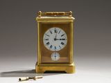 a gold clock with roman numerals and a key
