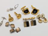 many different types of cufflinks and earrings on a white surface