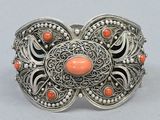 a close up of a silver bracelet with coral stones