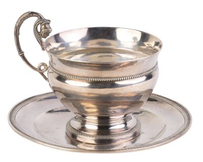 tasse à thé et soucoupe plaquées argent, posées sur une soucoupe, sur fond blanc