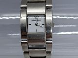 une montre-bracelet en argent avec un cadran blanc posée sur une surface blanche