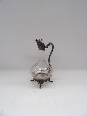 un pichet ancien en verre plaqué argent, posé sur un socle et muni d'une anse