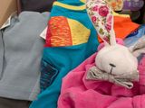 a cardboard box filled with clothes and a stuffed animal