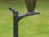 a statue of an owl sitting on a tree branch