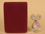 un petit flacon de parfum à côté d'une boîte rouge