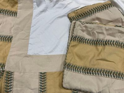 a white t - shirt sitting on top of a bed next to a pair of brown pants