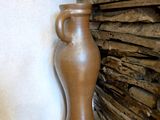 a brown vase sitting next to a pile of wood