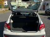 une voiture blanche dont le coffre est ouvert, garée sur un parking