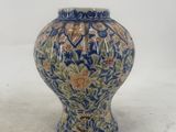 a blue and yellow vase sitting on a white surface