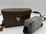 an old camera with a case and strap on a white surface