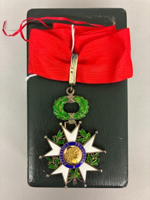 une petite médaille ornée d'un ruban rouge et d'une couronne