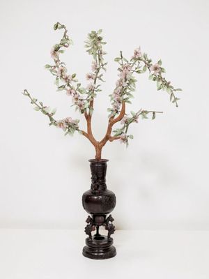 a black vase with a tree in it on a table