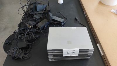un tas d'appareils électroniques posés sur une table à côté d'une lampe