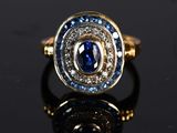 a close up of a gold ring with a blue sapphire and diamonds