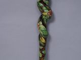 a close up of a wooden stick with a green and red design on it