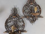 pair of ornate iron wall sconces with candle holders on a white wall