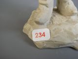 une petite statue représentant une personne assise sur un rocher, sur laquelle figure un numéro