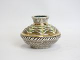 a silver and gold vase sitting on a white surface