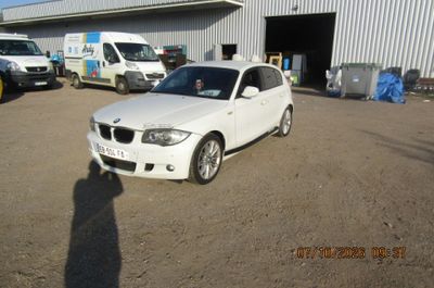 une BMW blanche garée devant un immeuble