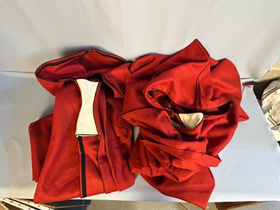 une robe rouge posée sur une chaise blanche, ornée d'un nœud rouge