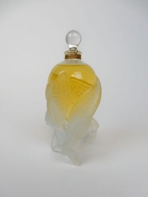une image représentant un flacon de parfum en verre posé sur une surface blanche