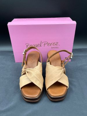 une paire de sandales beiges avec une boîte rose en arrière-plan