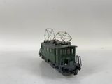 a green train on the tracks with a radio tower on top of it