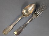 two silver spoons and a fork on a gray surface