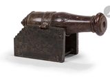 un vieux canon en bois posé sur un socle, sur fond blanc