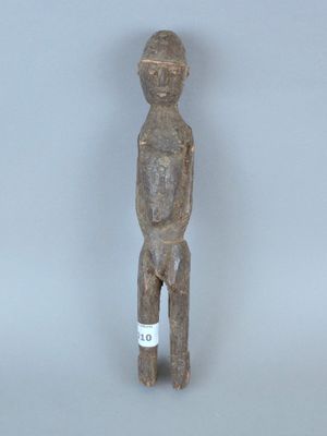 une vieille statue en bois représentant un homme, avec une étiquette sur la poitrine