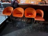 three orange bar stools sitting in front of a counter
