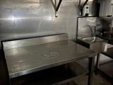 une grande cuisine en inox équipée d'une cuisinière et d'un évier