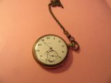une montre de poche en or à laquelle est accrochée une chaîne sur le côté