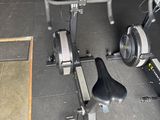two stationary exercise bikes in a garage with a bench