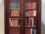 an antique bookcase with many books and a clock on top of it