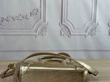 golden purse on a wooden table with a white wall in the background