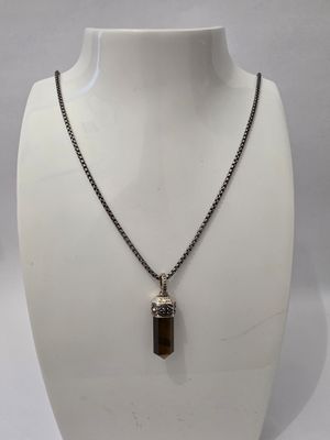a white mannequin with a brown stone pendant on it