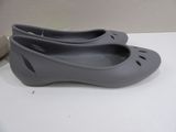 grey crocs shoes on a white table with a book
