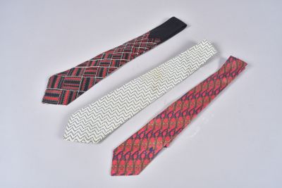 three different colored ties laying next to each other on a white surface