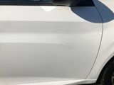 a white car that has been dented and is parked on the side of the road