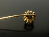a gold spoon with a flower on it on a black surface