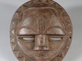 gros plan d'un masque en bois sur une surface blanche