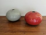 two vases sitting on a wooden table next to each other