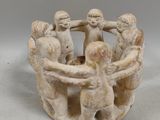 several figurines of people holding hands around a bowl