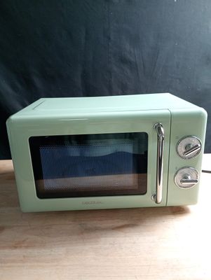 un petit micro-ondes vert posé sur une table en bois